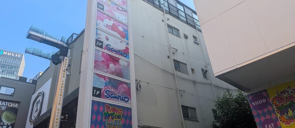 A building wall lined with Sanrio signs, with the KAWAII MONSTER LAND sign below